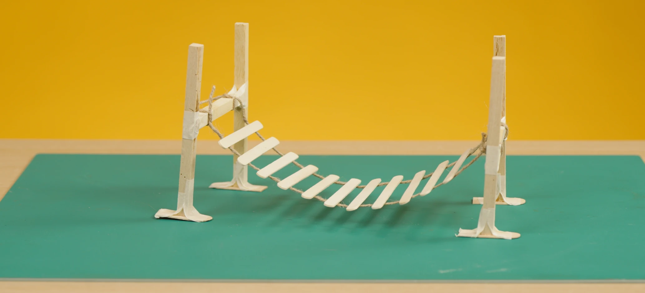 Model of a wobbly bridge made with wooden uprights and a bridge made from lollipop sticks.