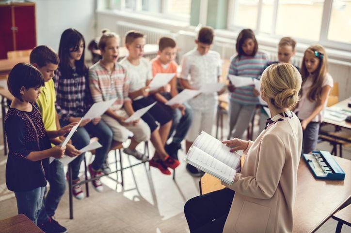 children and their teacher learning sheet music