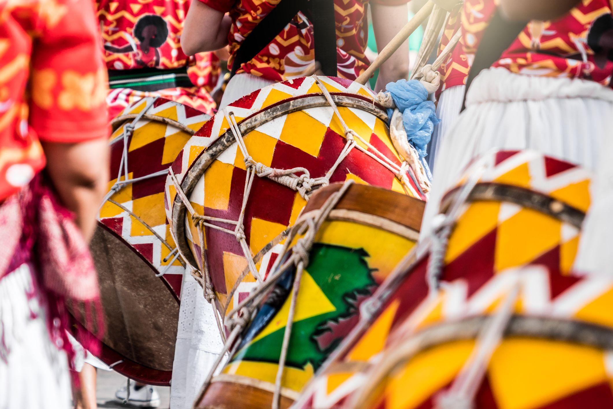 Performers playing colourful patterned drums during a cultural procession.