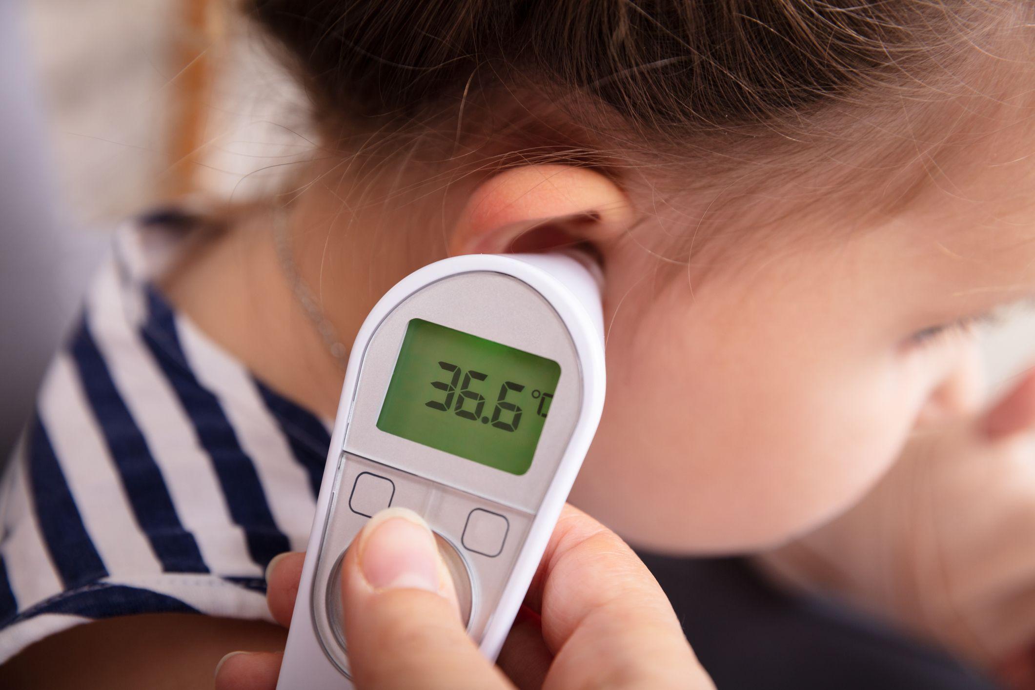 Child having their temperature taken with a digital device