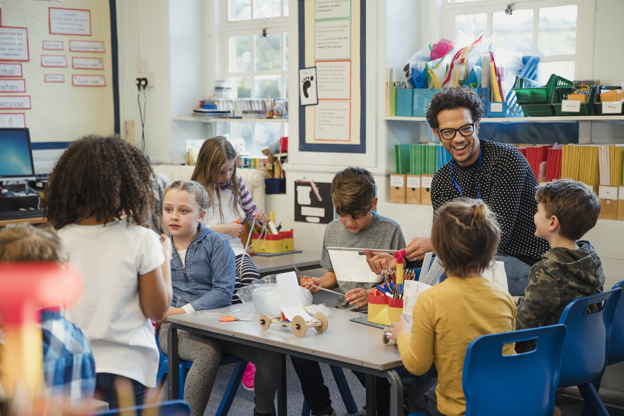 Teacher and children in Design and technology lesson building a wooden car