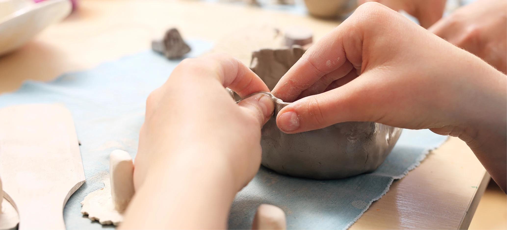 Close-up of a child’s hands shaping clay into a bowl during a hands-on art and craft activity.