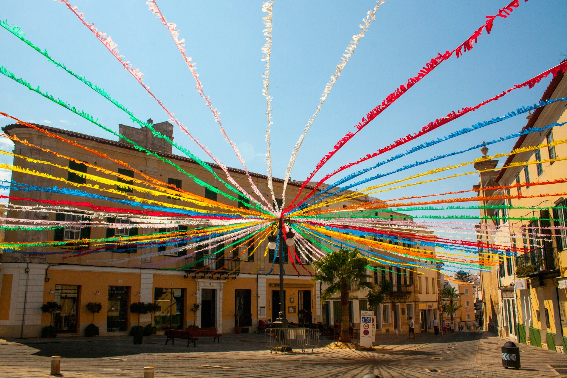 Colourful festive ribbons stretch across a street during a celebration.