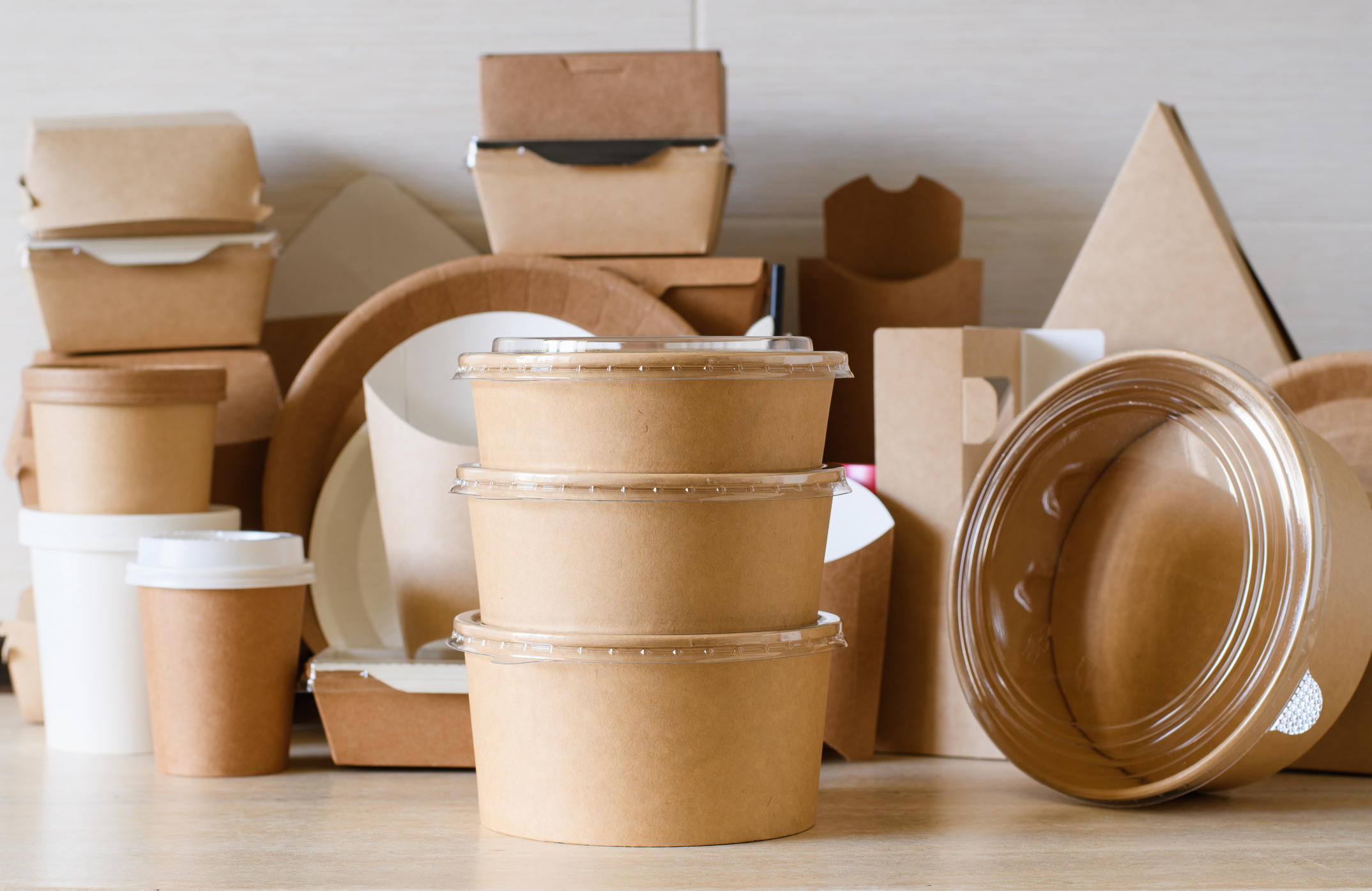 Assorted brown cardboard food containers and cups arranged on a table.