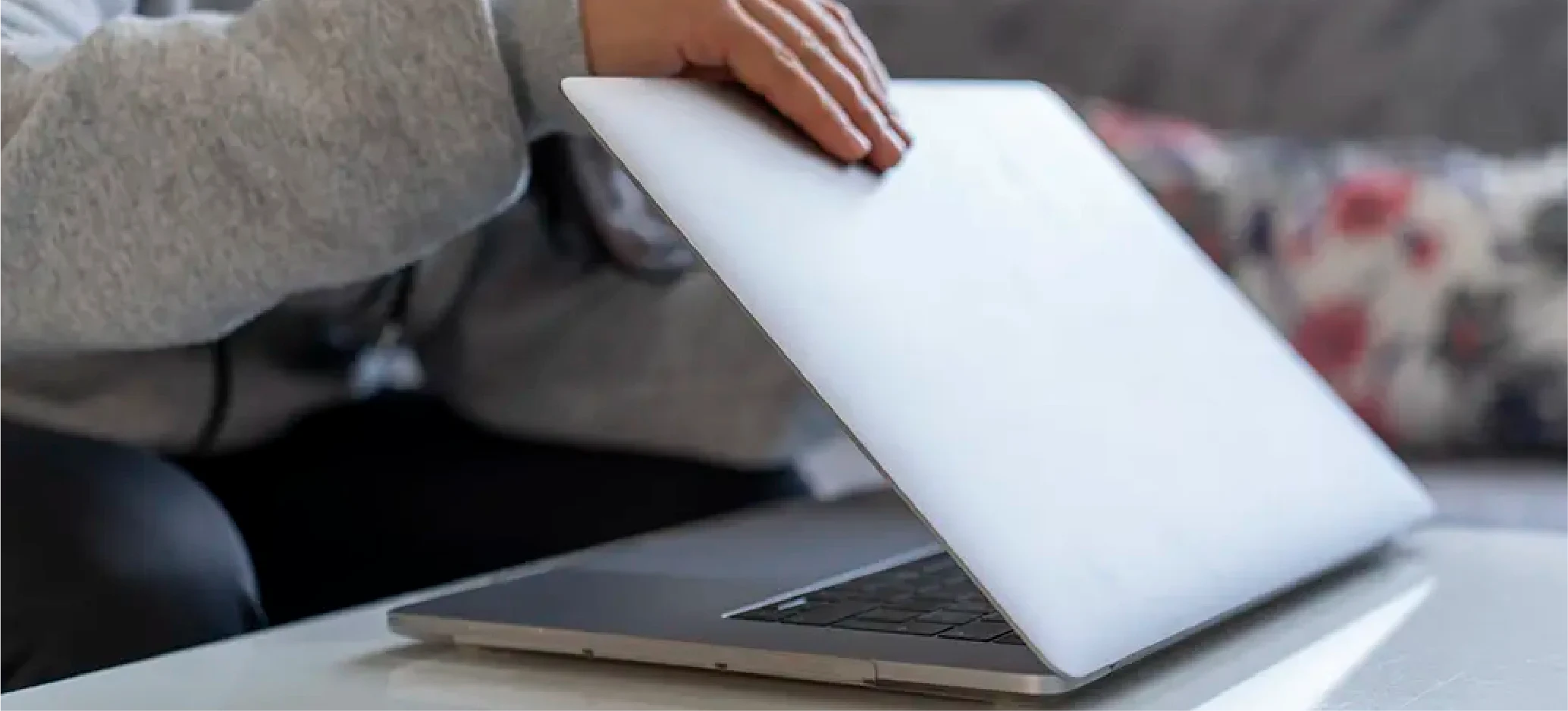 Person opening a laptop on a table.
