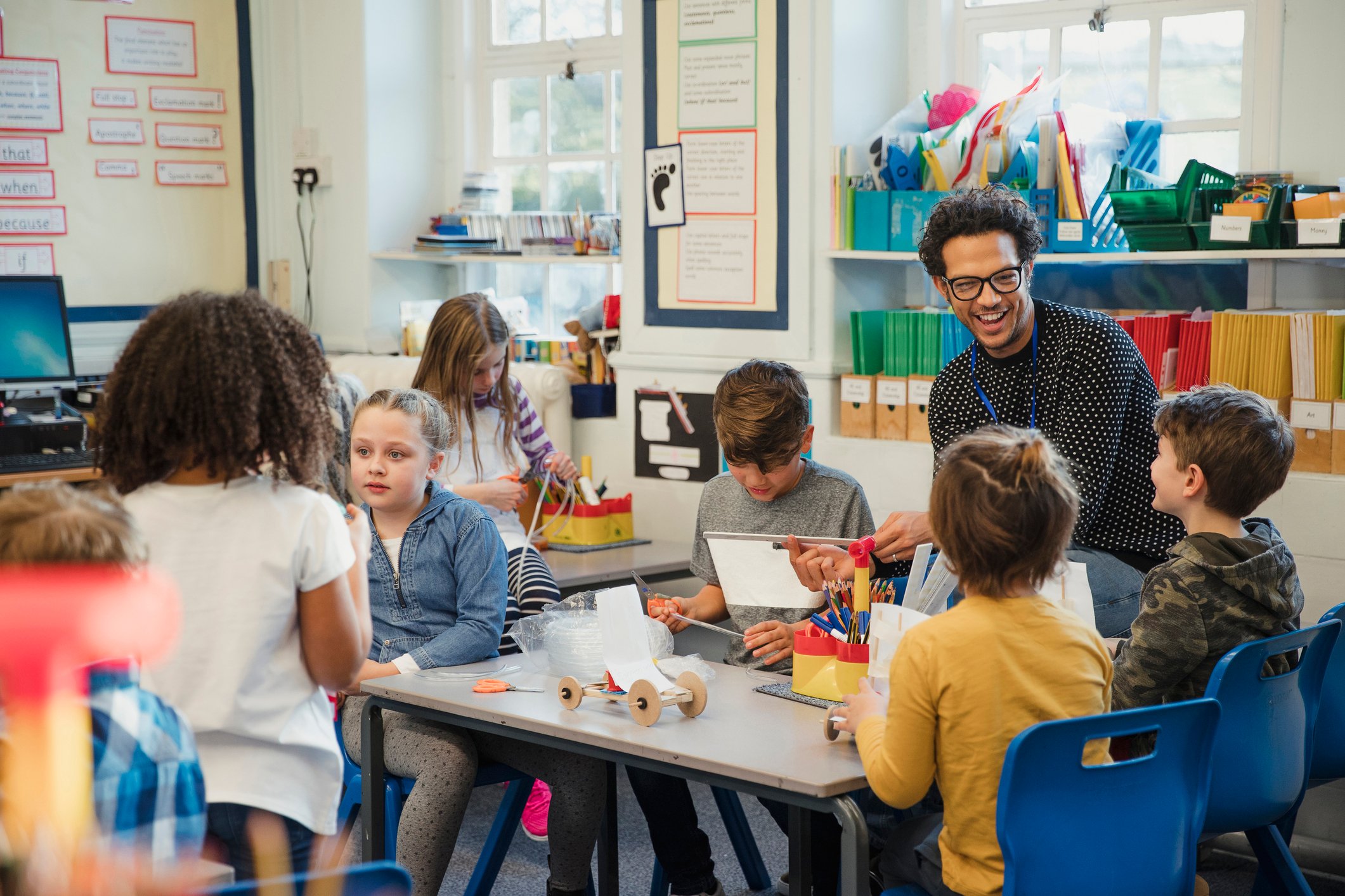 Teacher and children in Design and technology lesson building a wooden car