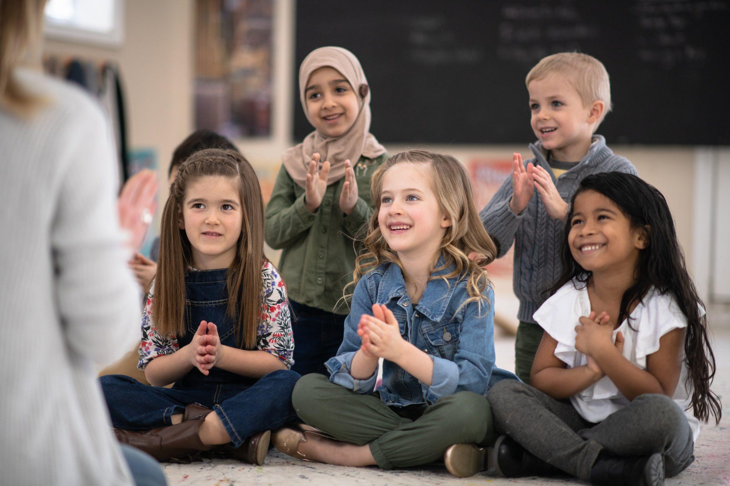 children sitting on the floor and clapping