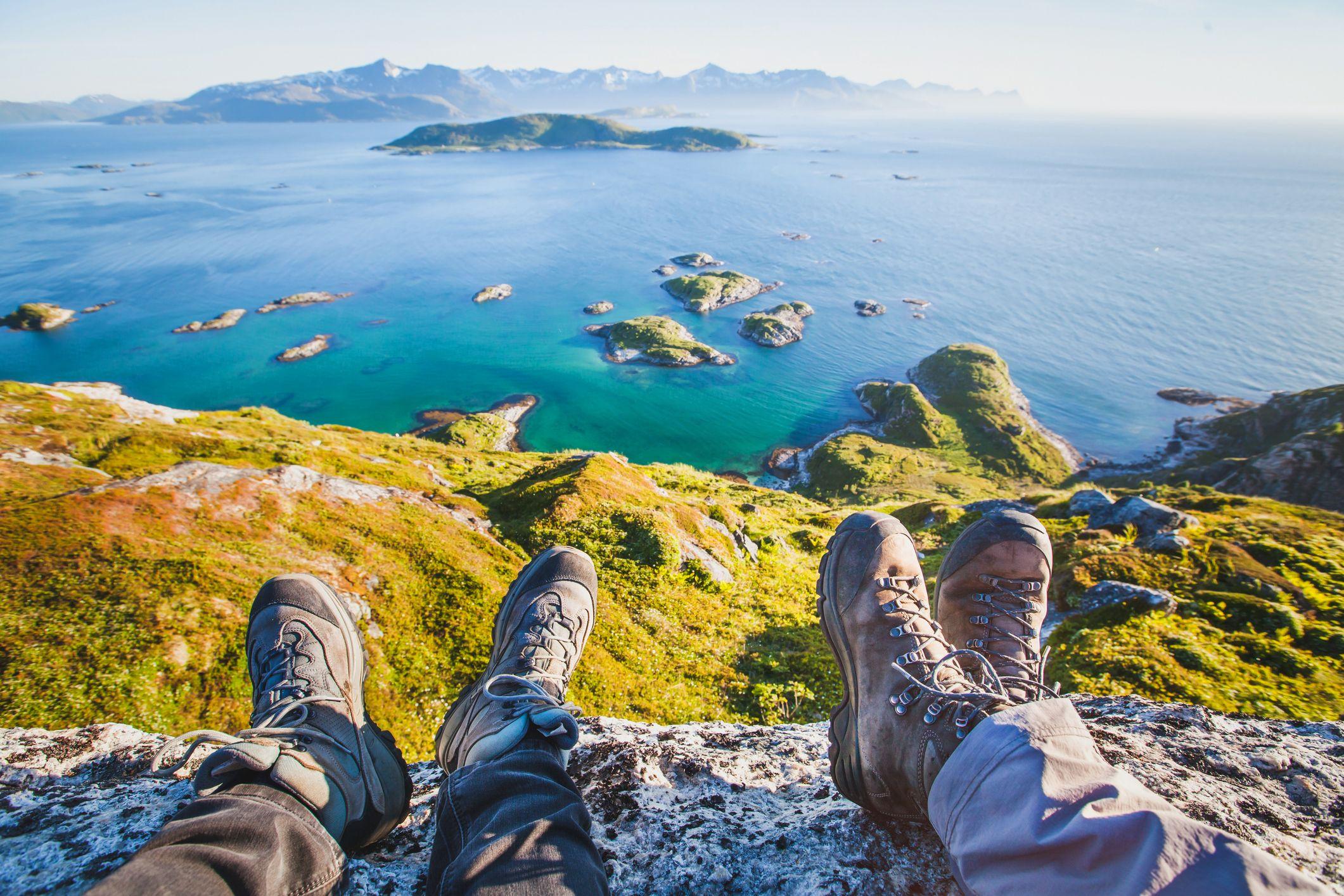 People enjoying the view over the sea from a cliff-edge wearing walking boots