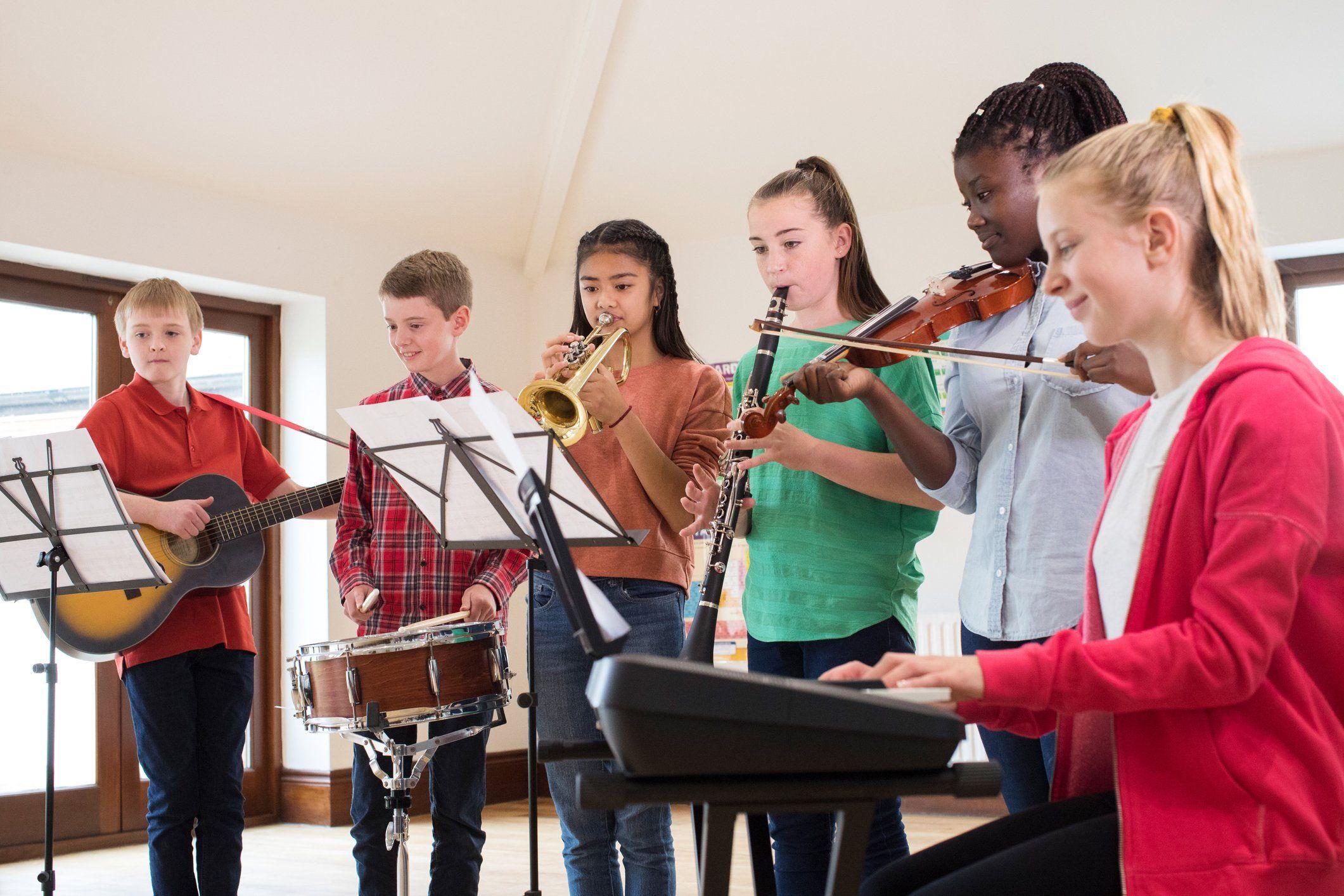 A group of children playing musical instruments together in a classroom performance.