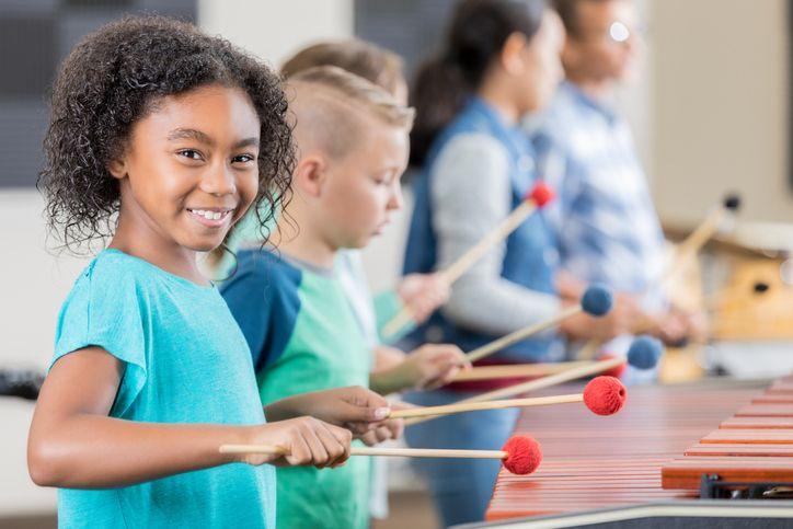 Children playing xylophones with mallets during a classroom music lesson.
