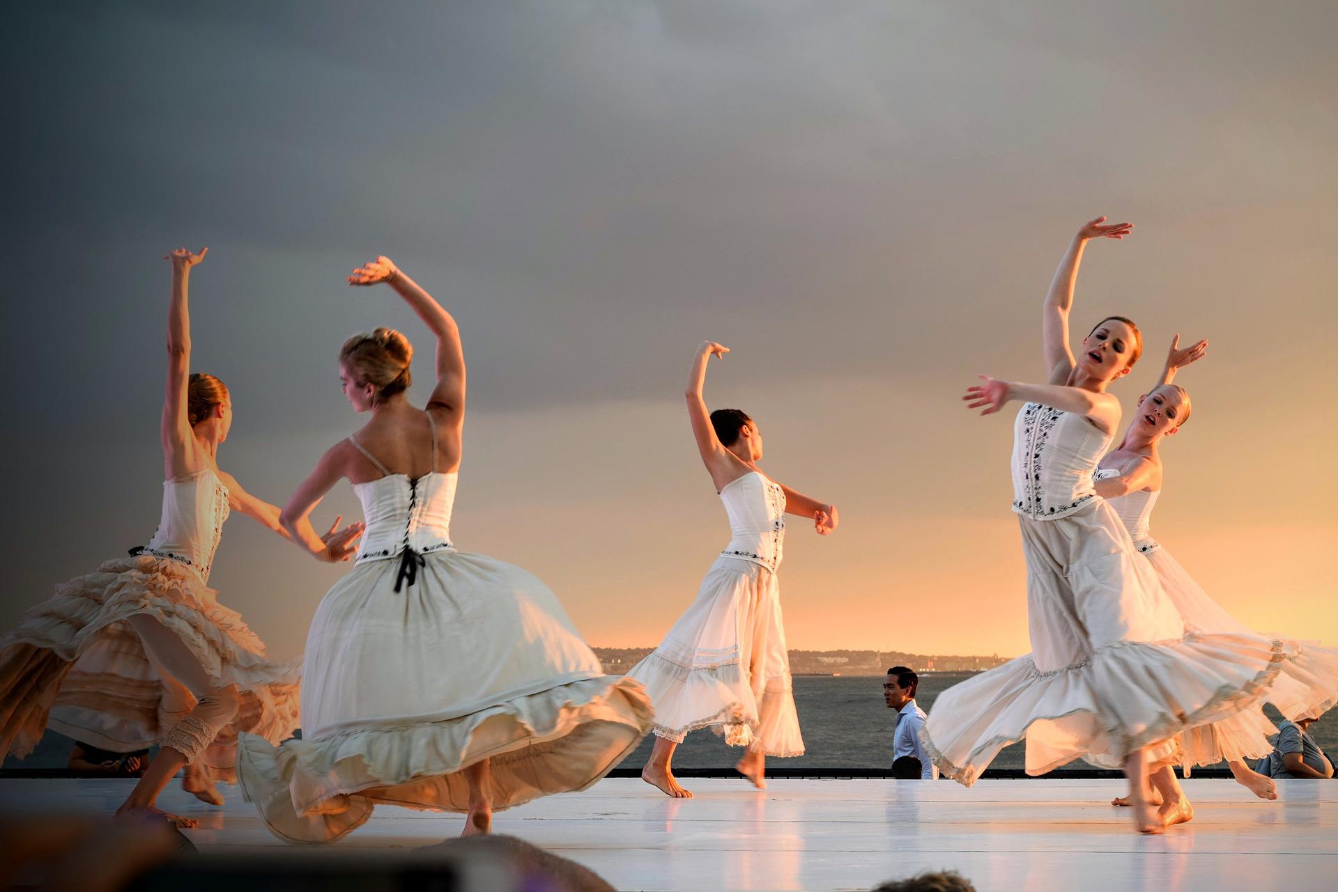Ladies dancing in white dresses at sunset