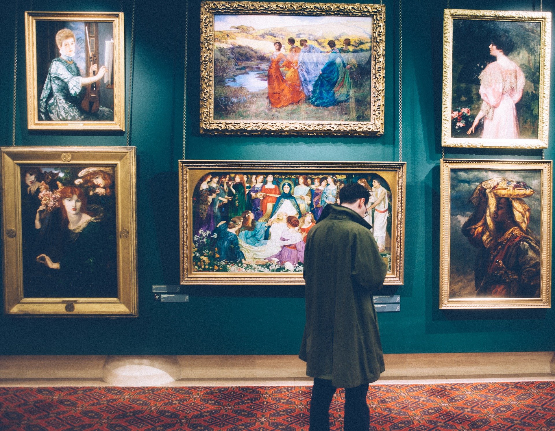 man lookin at paintings in an art gallery
