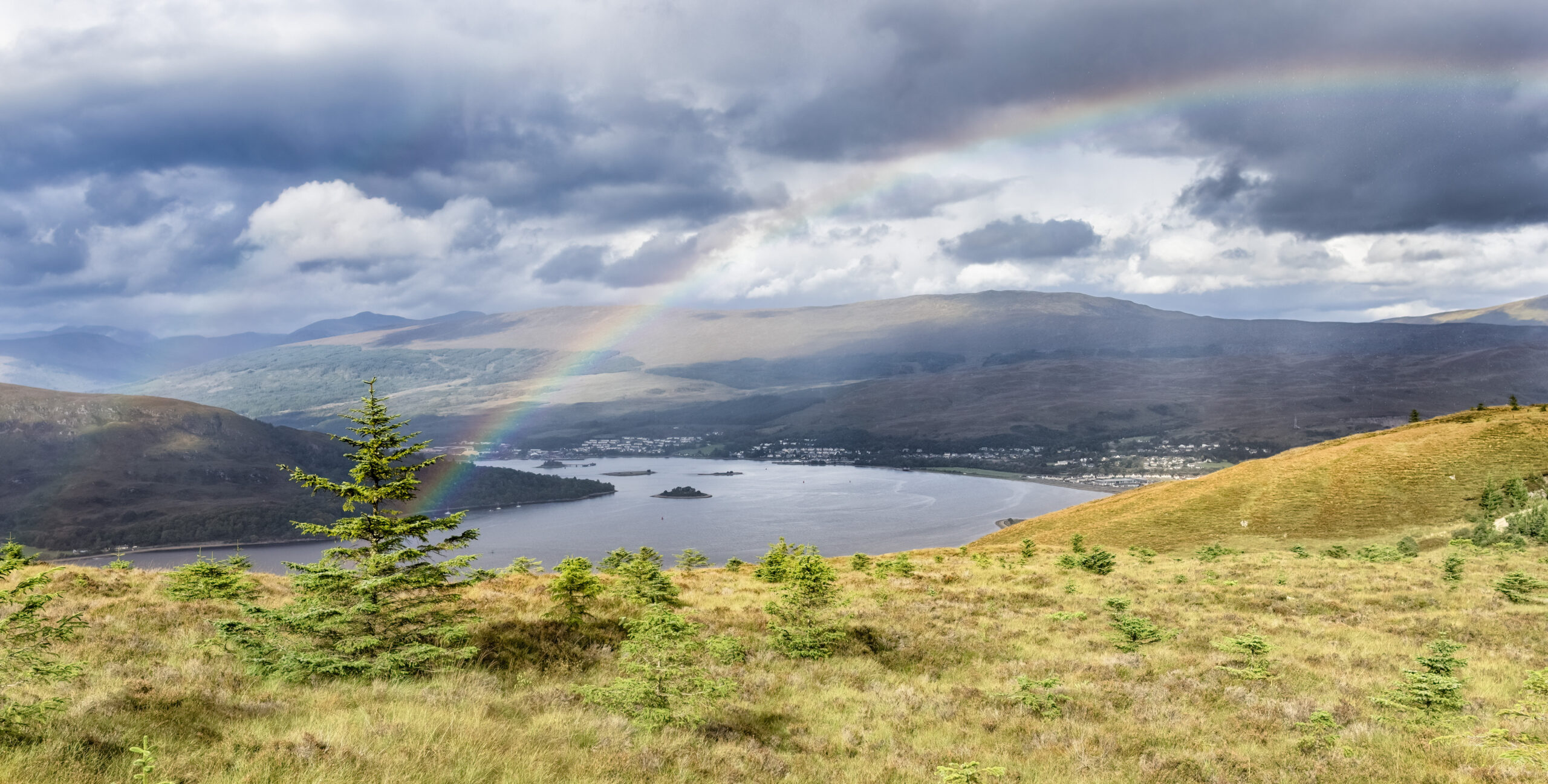 rainbow and dark clouds over the hills