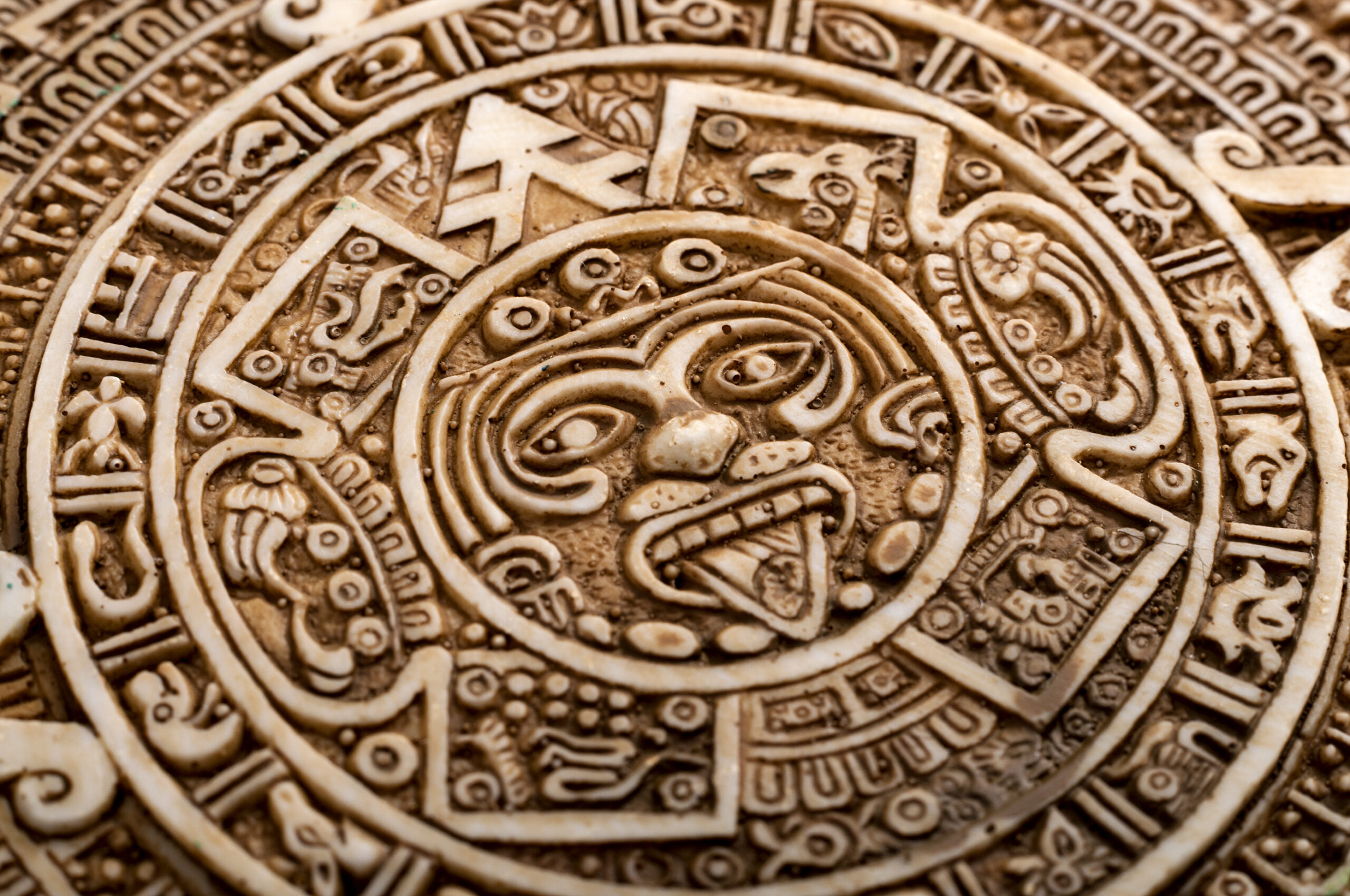 Close-up of the Aztec calendar stone with carved face and symbols.