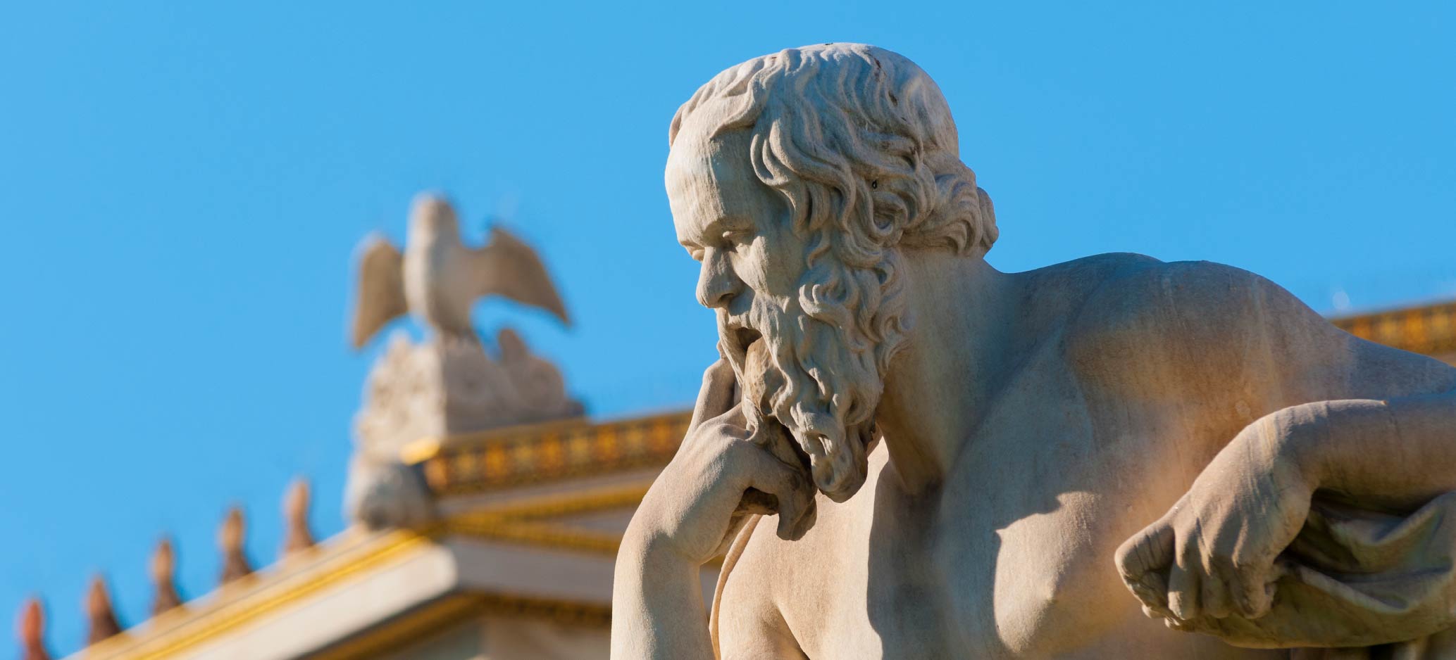 Marble statue of an ancient Greek philosopher resting his chin on his hand in a thoughtful pose.