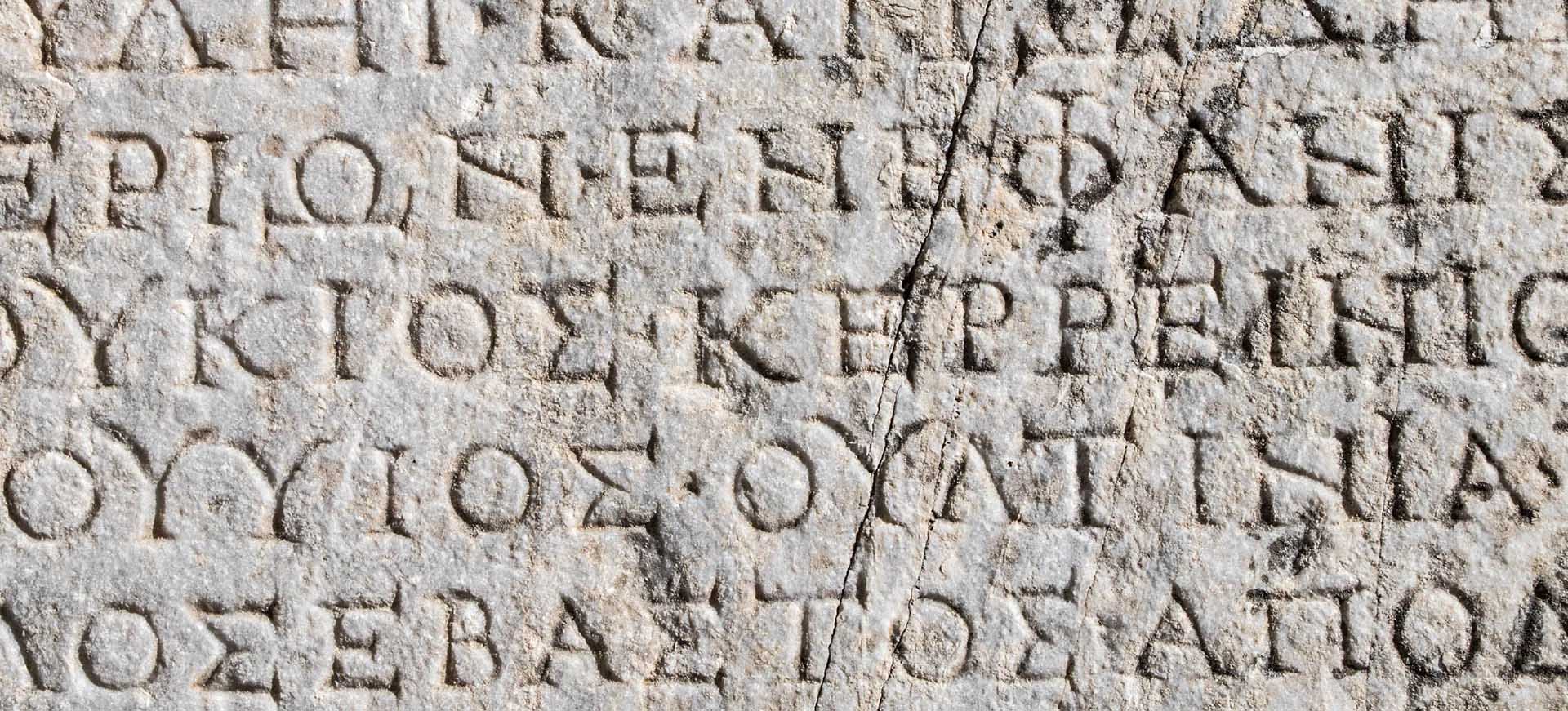 Close-up of an ancient stone inscription carved with Greek letters.