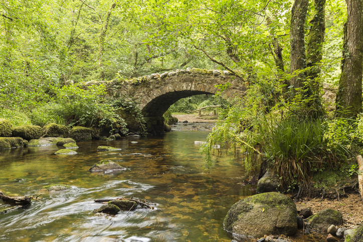 A riverside image of Hisley Bridge an old packhorse bridge over the river Bovey, shot at Dartmoor, Devon, England, UK