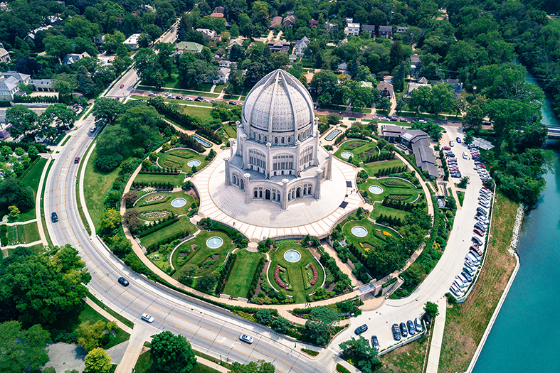 Aerial view of the Baha'i House of Worship surrounded by lush gardens and trees.