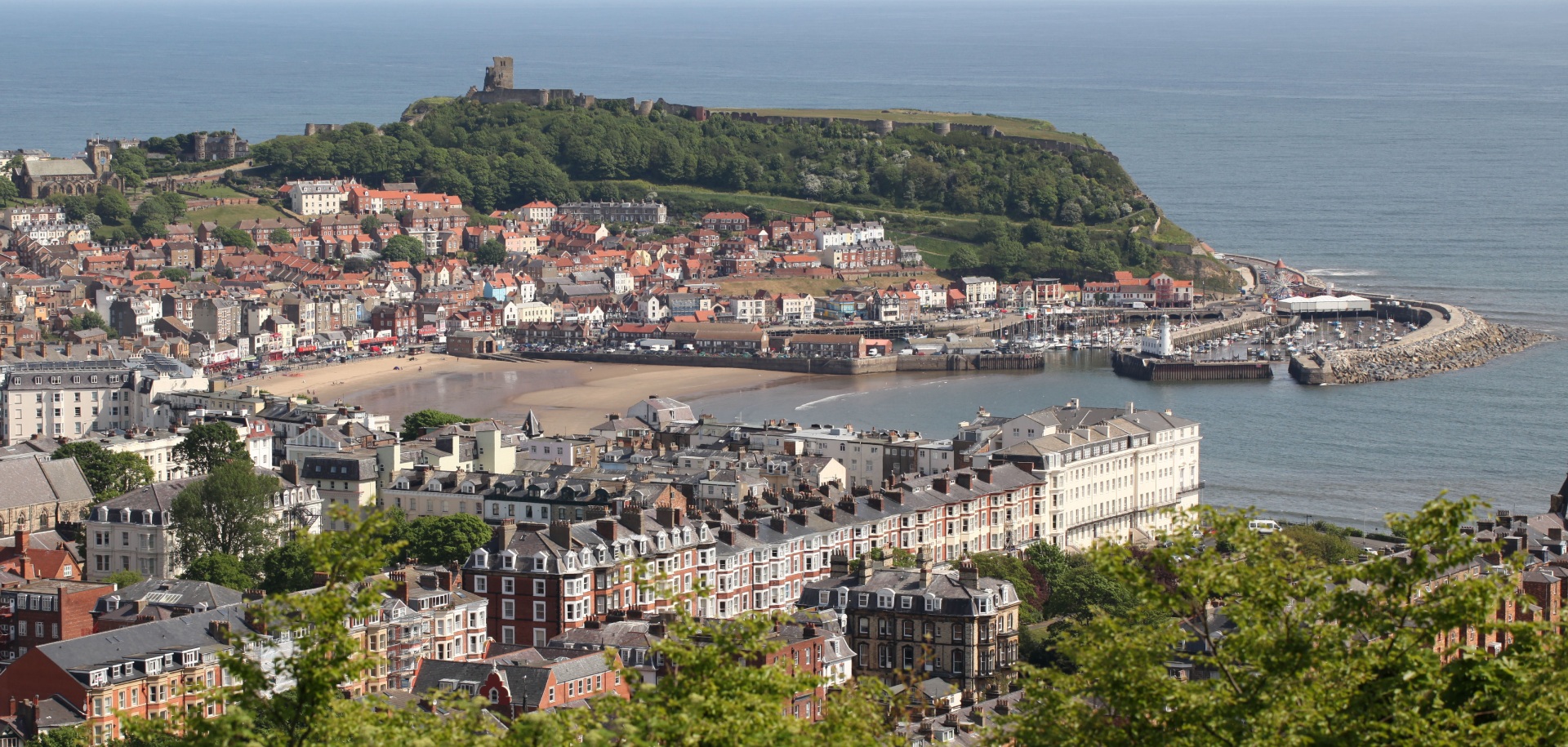 A panoramic view of Scarborough, a coastal town in North Yorkshire, with the historic Scarborough Castle overlooking the sea.