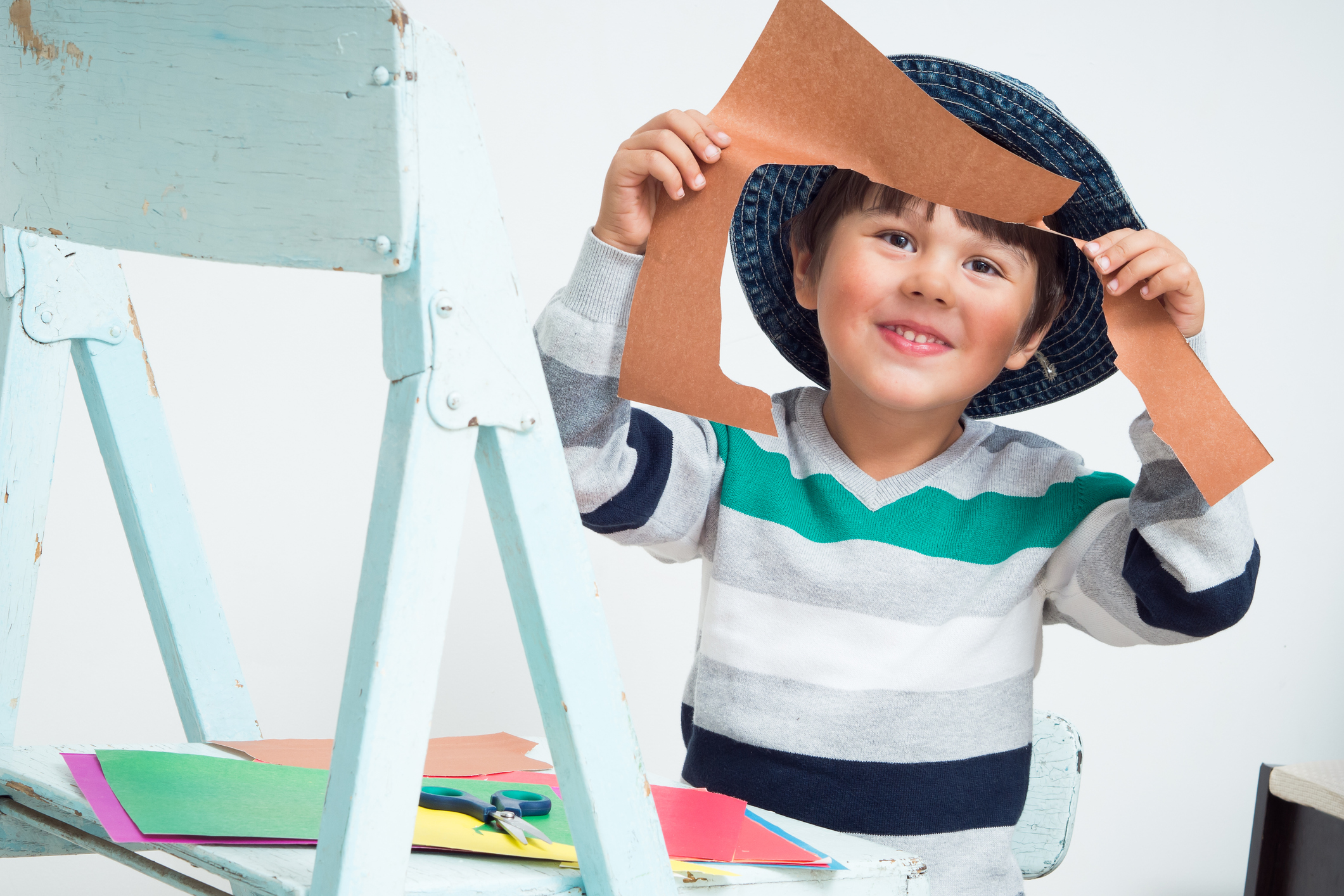 Small boy cuts coloured paper with scissors