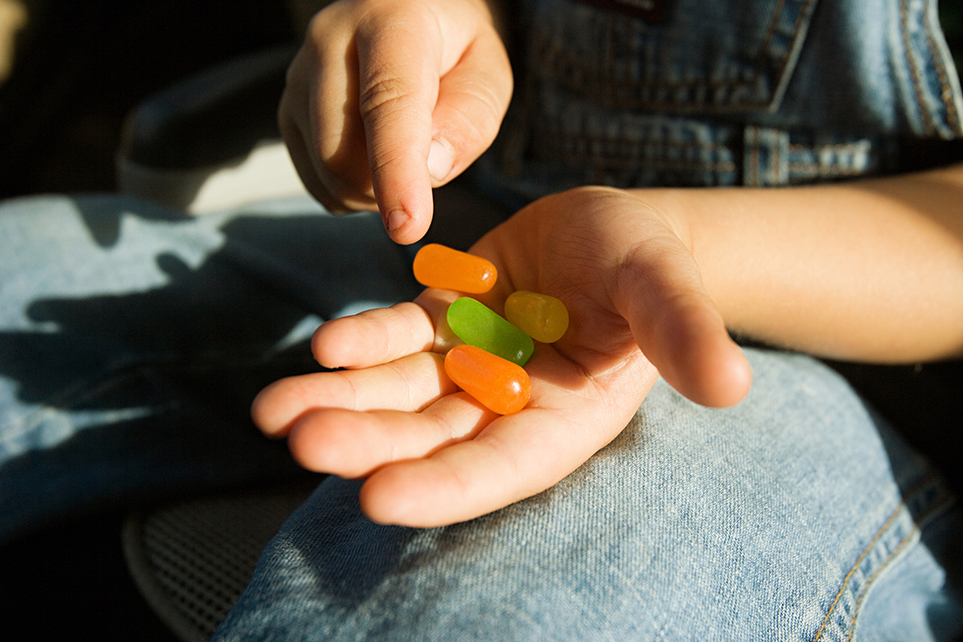 Close-up of a child’s hand holding colourful jelly sweets in the sunlight.