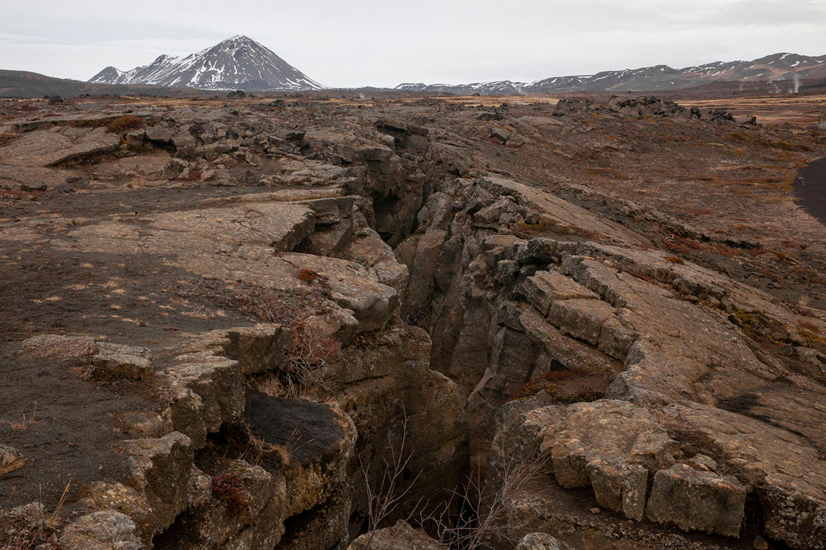 Tectonic plate boundary fissure with distant snow-capped mountain