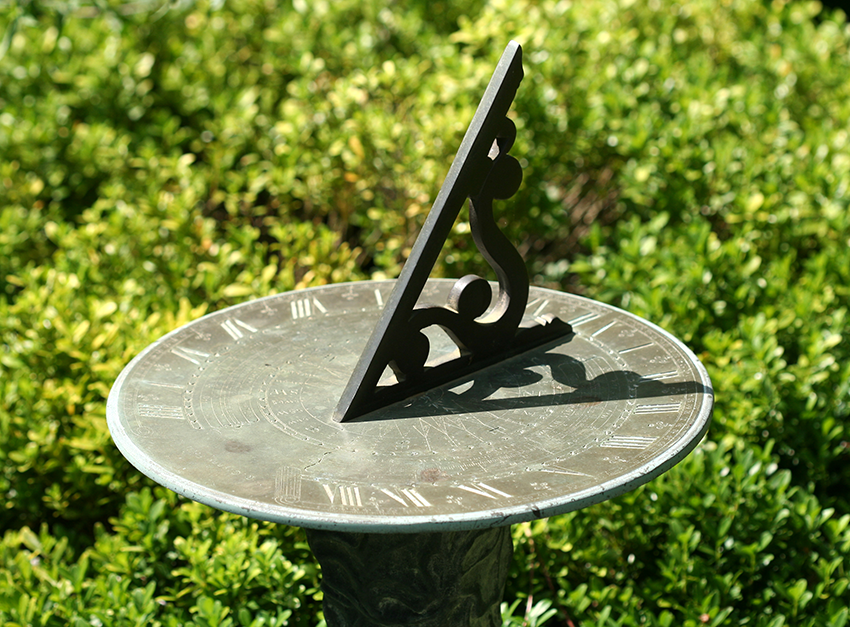 Traditional metal sundial with Roman numerals in a garden