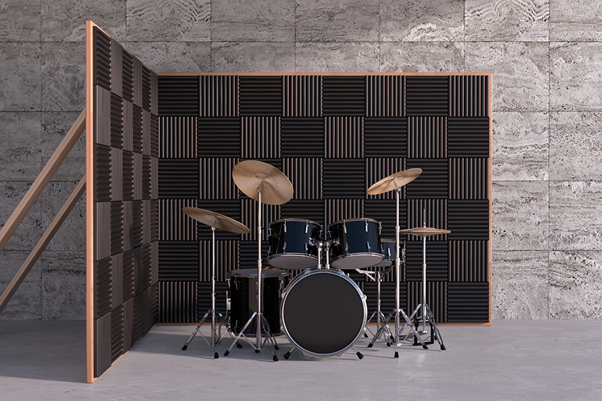 Drum kit set up in front of black acoustic foam panels in a grey room