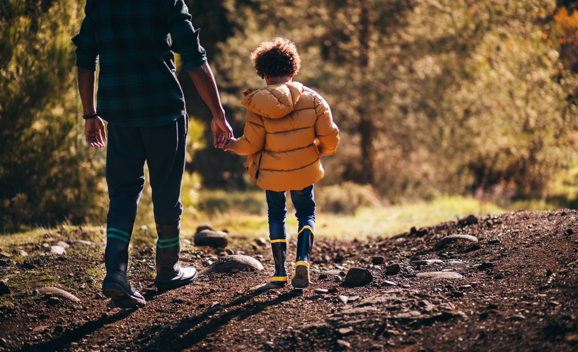 child walking with parent in the woods