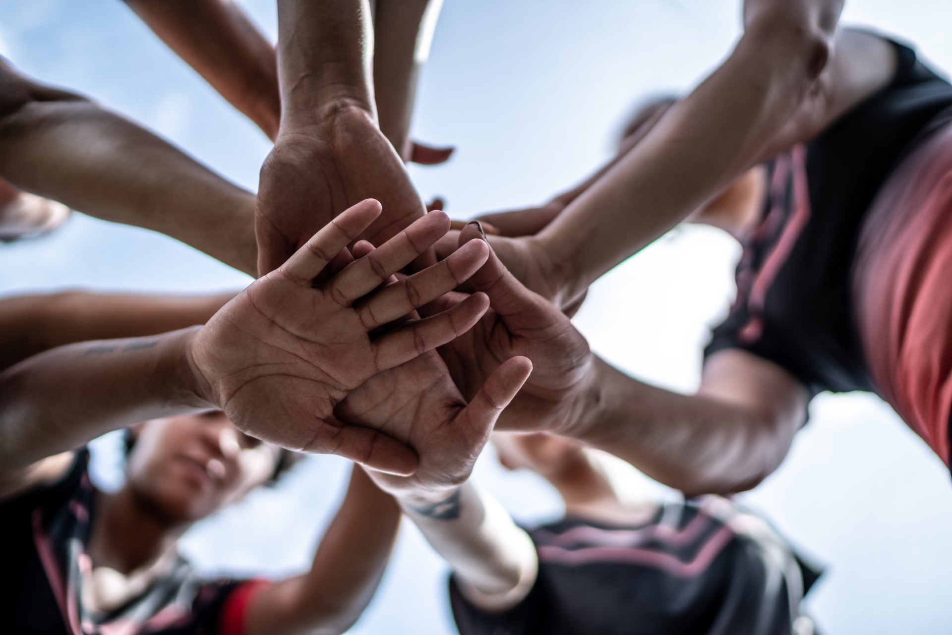 A group of people put their hands together in the middle of their group