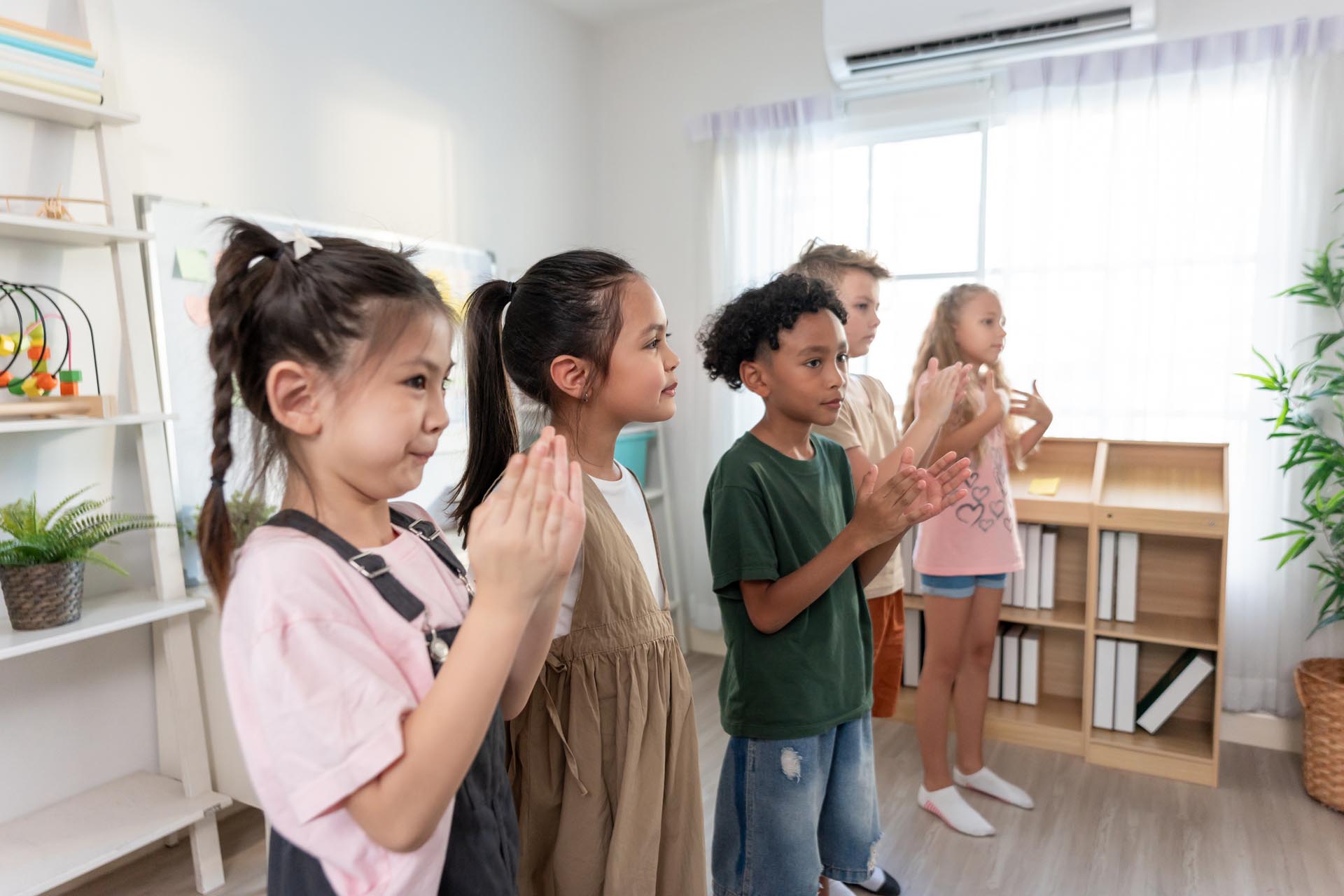 A diverse group of students clapping their hands together during a classroom activity at school.