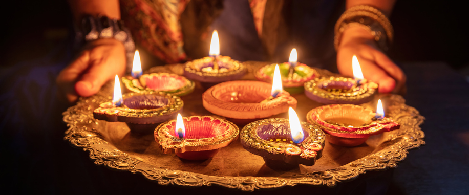 Lit clay diyas arranged on a decorative tray during a Diwali celebration.