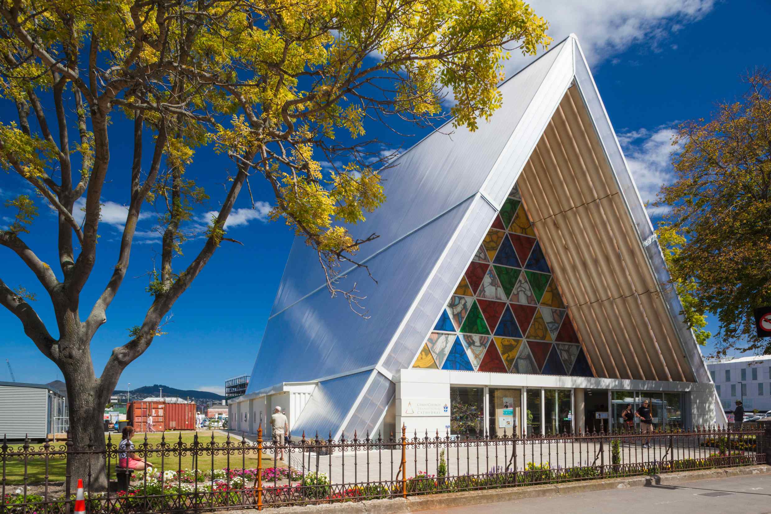 A triangular modern church building with colourful stained-glass windows and a white frame.