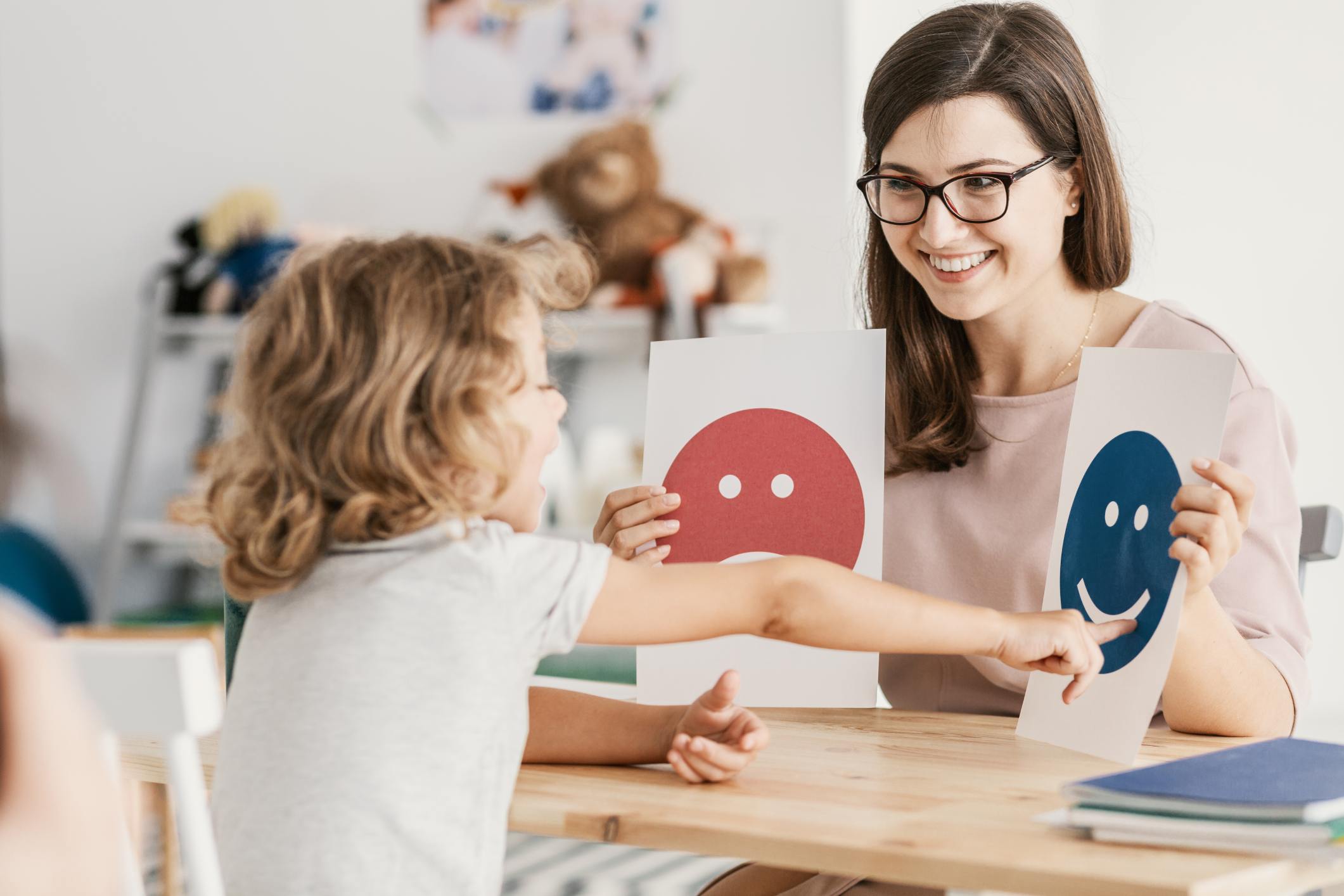 Teacher helping child identify emotions with happy and sad faces