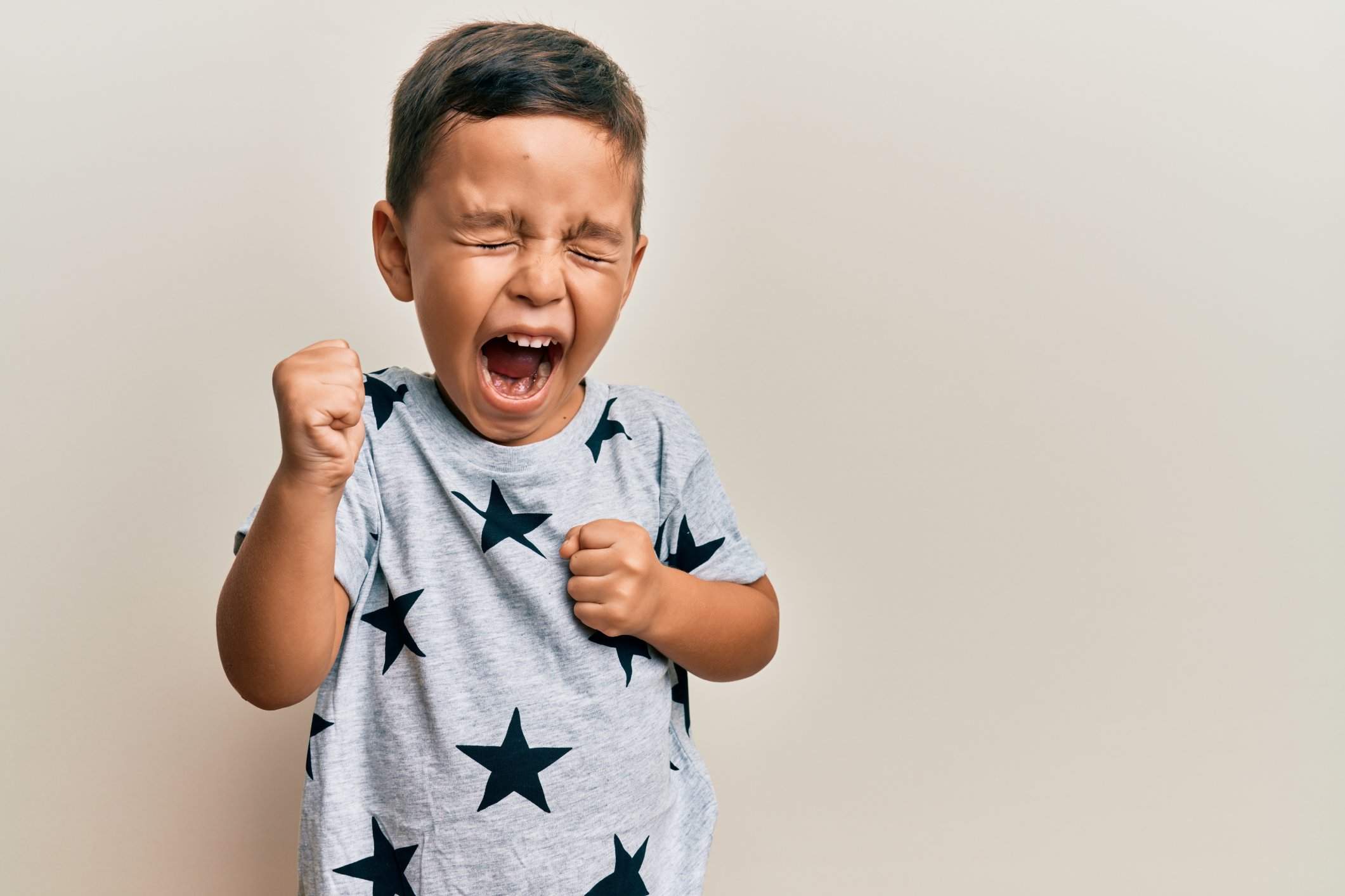 Child shouting with fists clenched showing anger