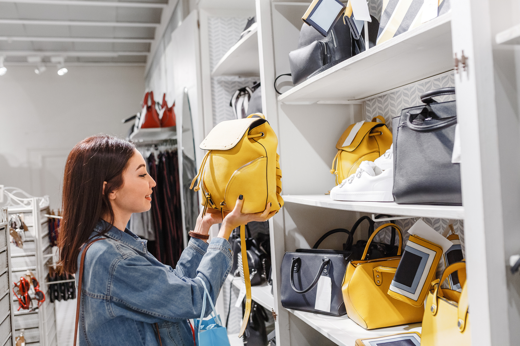 A woman is inspecting purses on display in a fashion store.