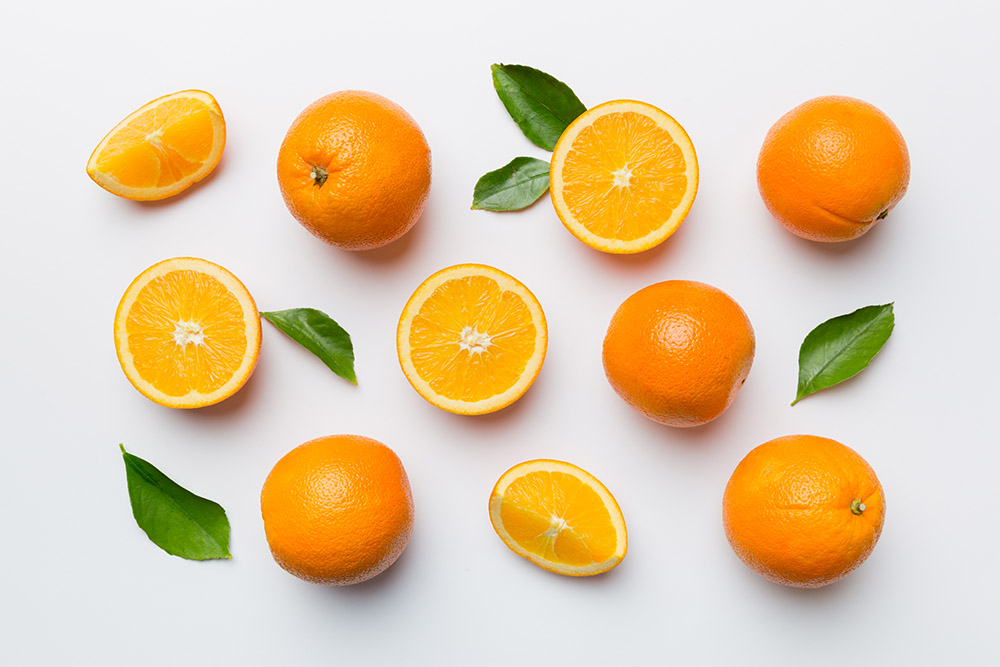 Fresh oranges, whole, halved and sliced arranged in a pattern.