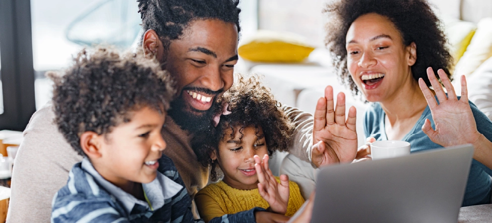Family smiling and waving during a video call at home