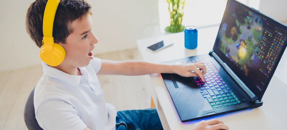 Child wearing yellow headphones while playing a game on a laptop