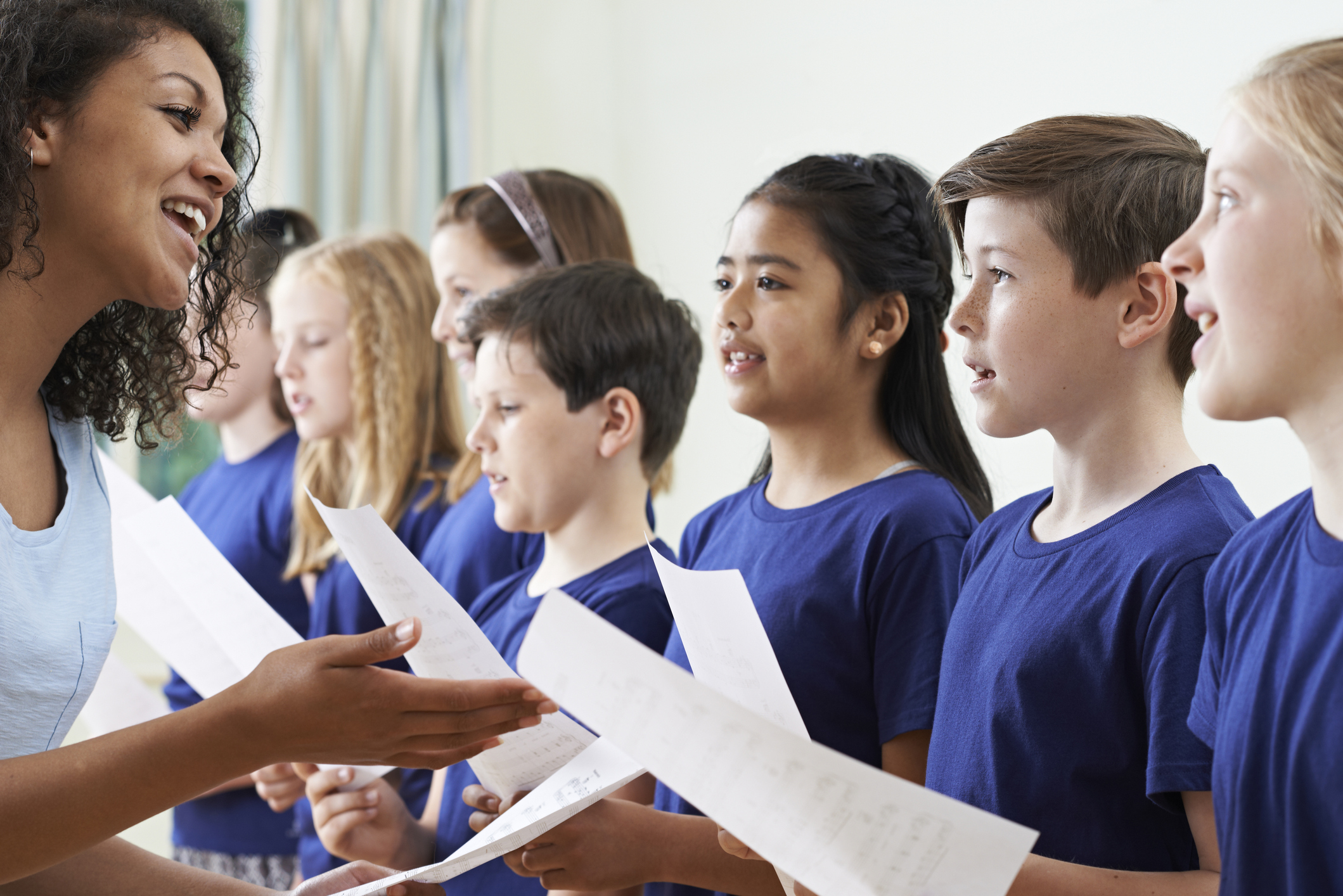 Group Of School Children With Teacher Singing In Choir