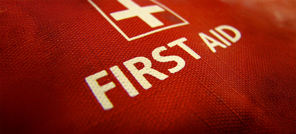 Close-up of a red first aid kit with a white cross and the words 'First Aid'.