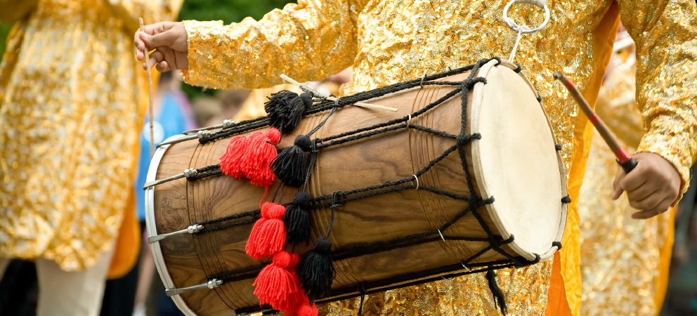 Musician's hands playing a traditional dhol drum.