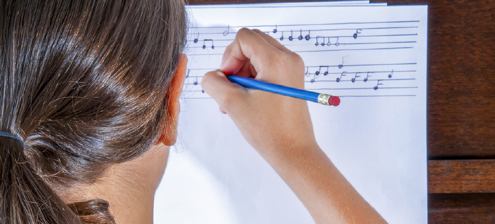 Young girl writing musical notes for composition.