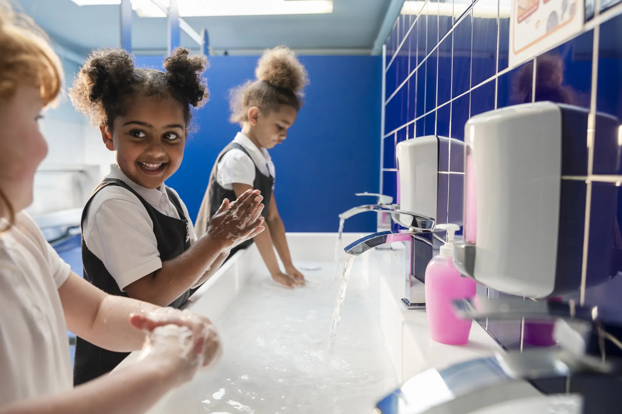 Primary school pupils washing their hands with soap at classroom sinks