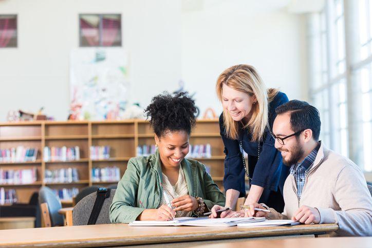Three teachers sat around table looking at notes
