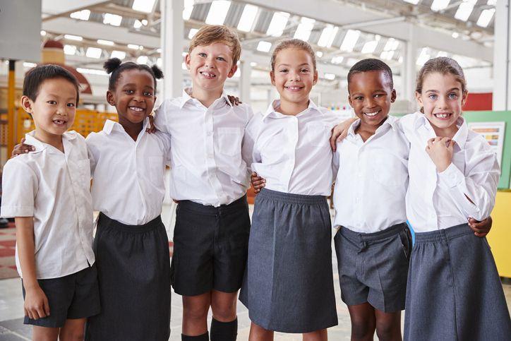 Six primary school pupils smiling together in school uniform