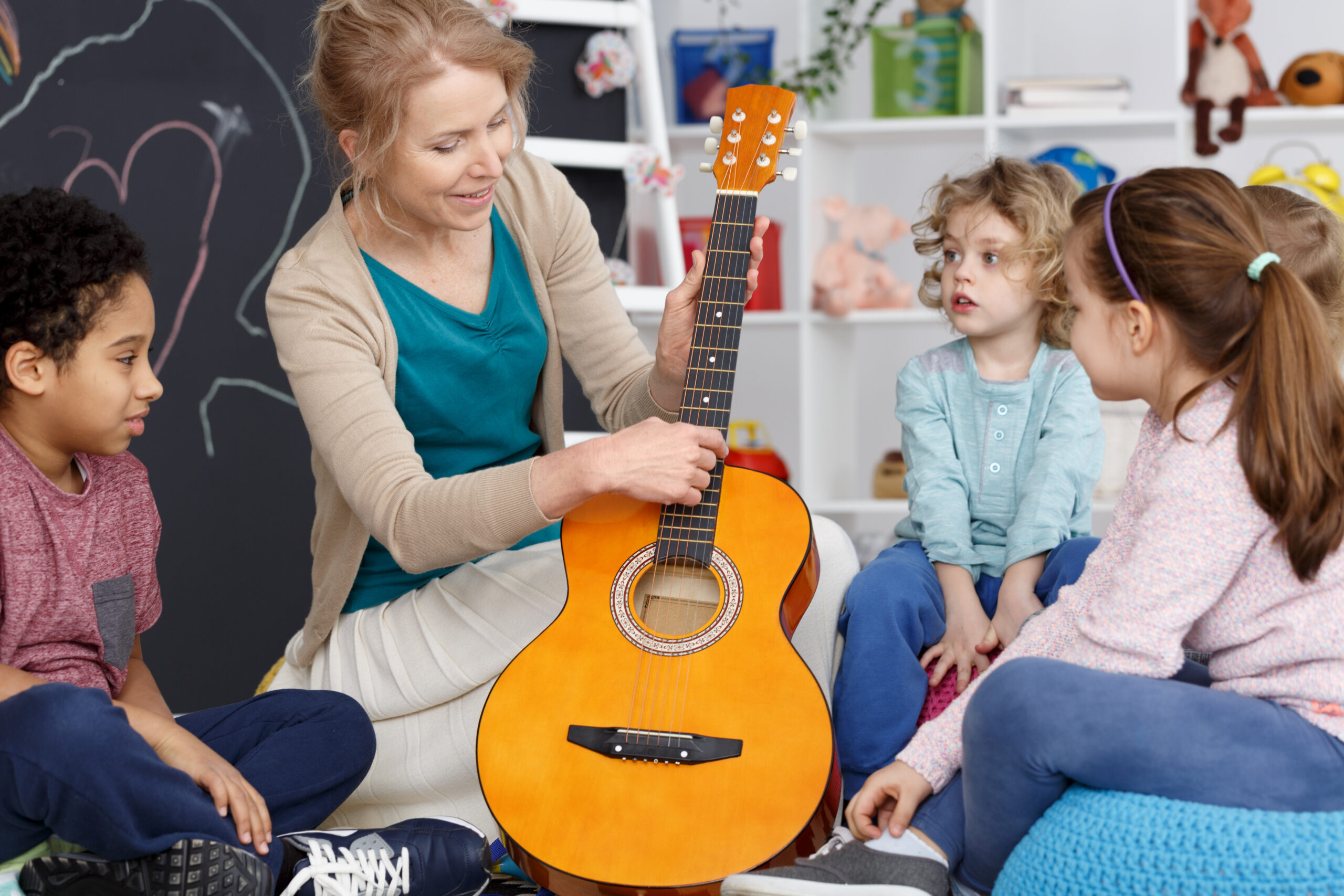 Music teacher showing pupils guitar