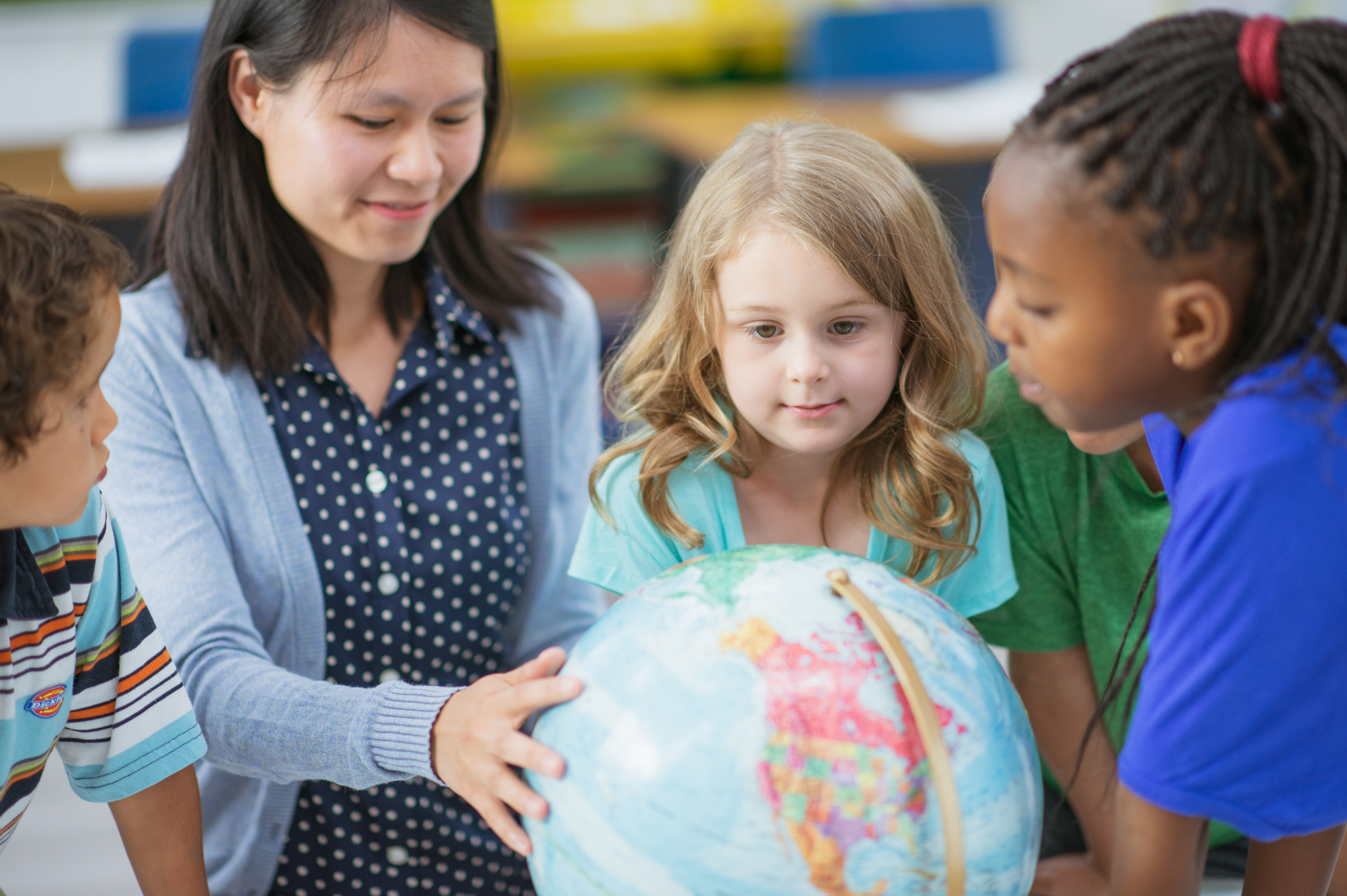 Reception children standing around a globe