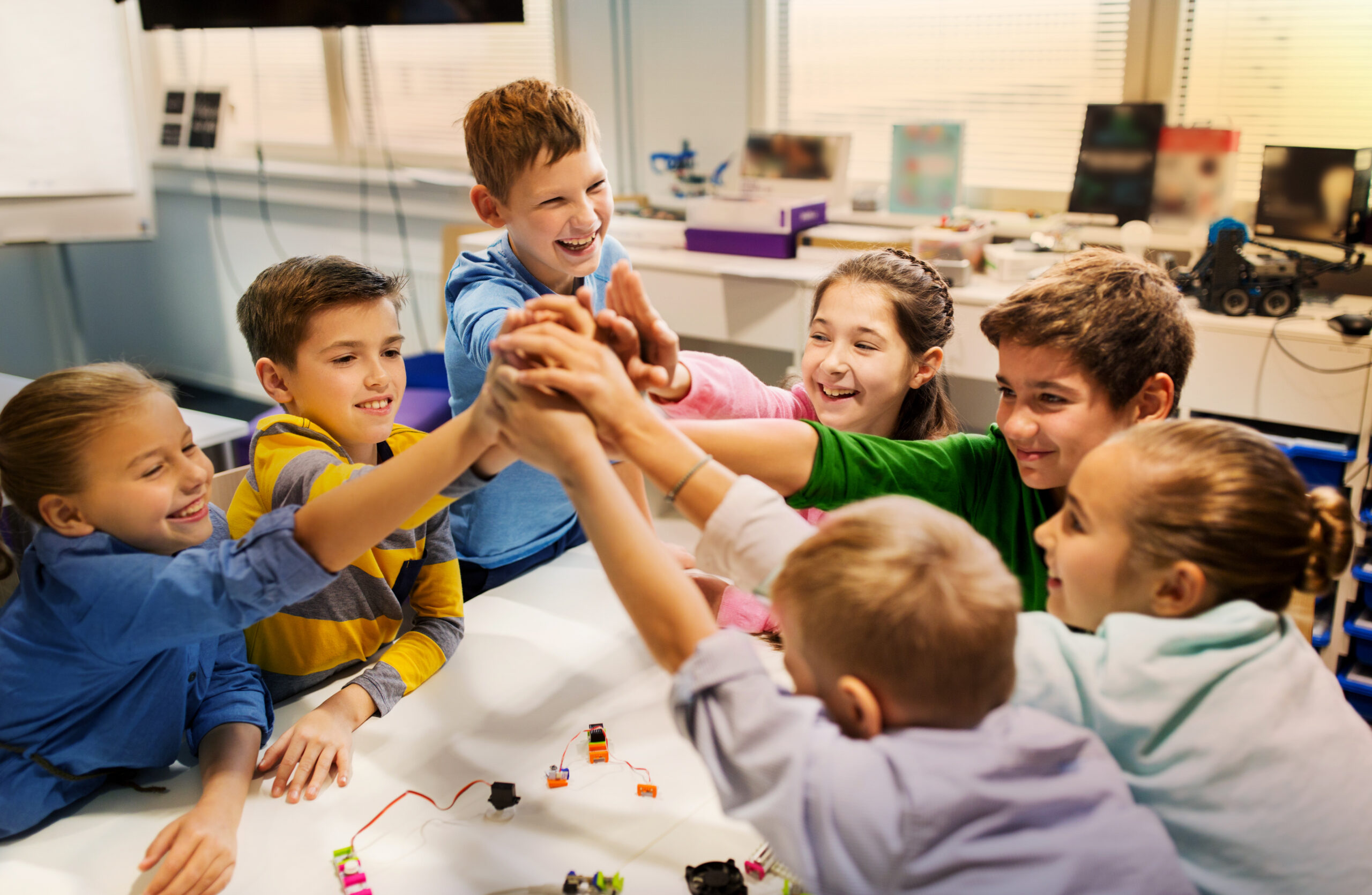 Group of children in class working together and high fiving