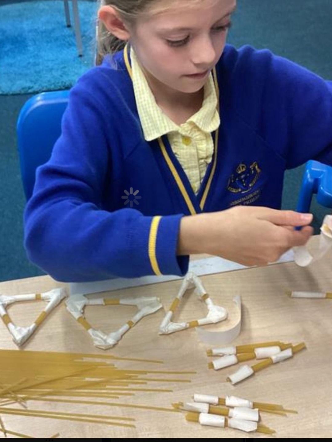 Pupil assembling spaghetti and tape triangles for a model structure.